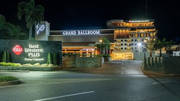 A hotel with a prominent 'Grand Ballroom' sign, a 'Best Western PLUS' sign, and a well-lit entrance.