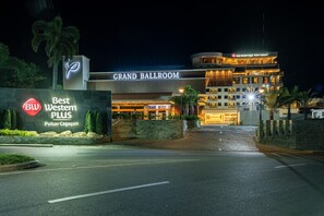Un hôtel reconnaissable à son grand panneau indiquant « Grand Ballroom », à son panneau « Best Western PLUS » et à son entrée bien éclairée.
