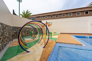 Un espace de jeux pour enfants avec des structures d’escalade colorées et une piscine.