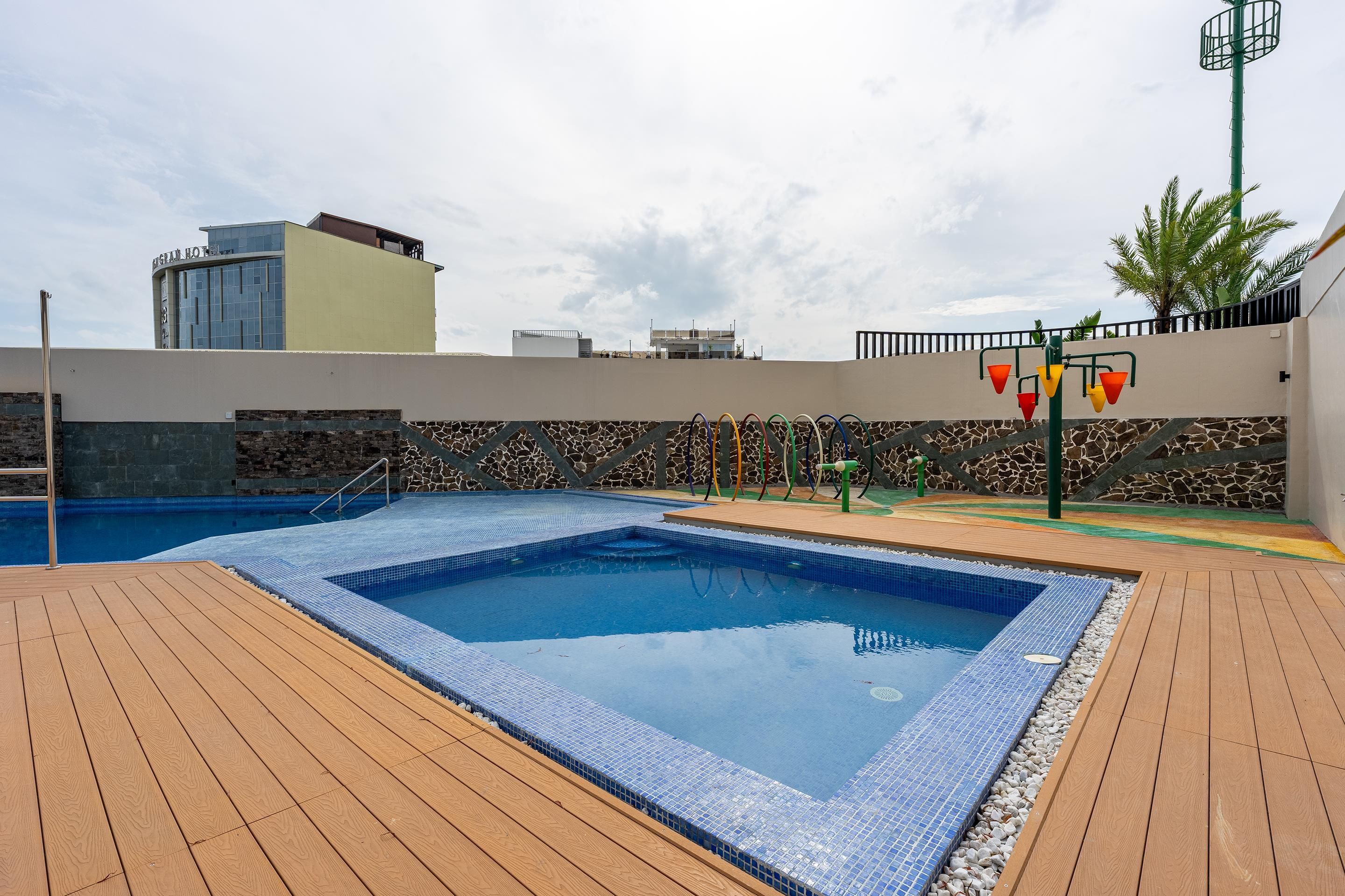 A swimming pool with a tiled edge, surrounded by a wooden deck.