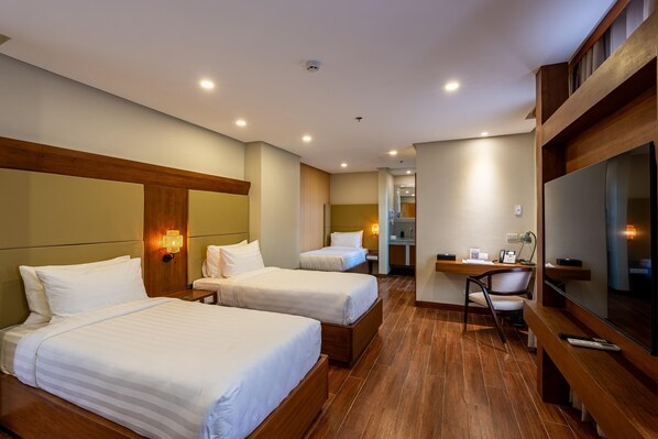 Une chambre d’hôtel avec deux lits, un bureau, une chaise et un téléviseur.