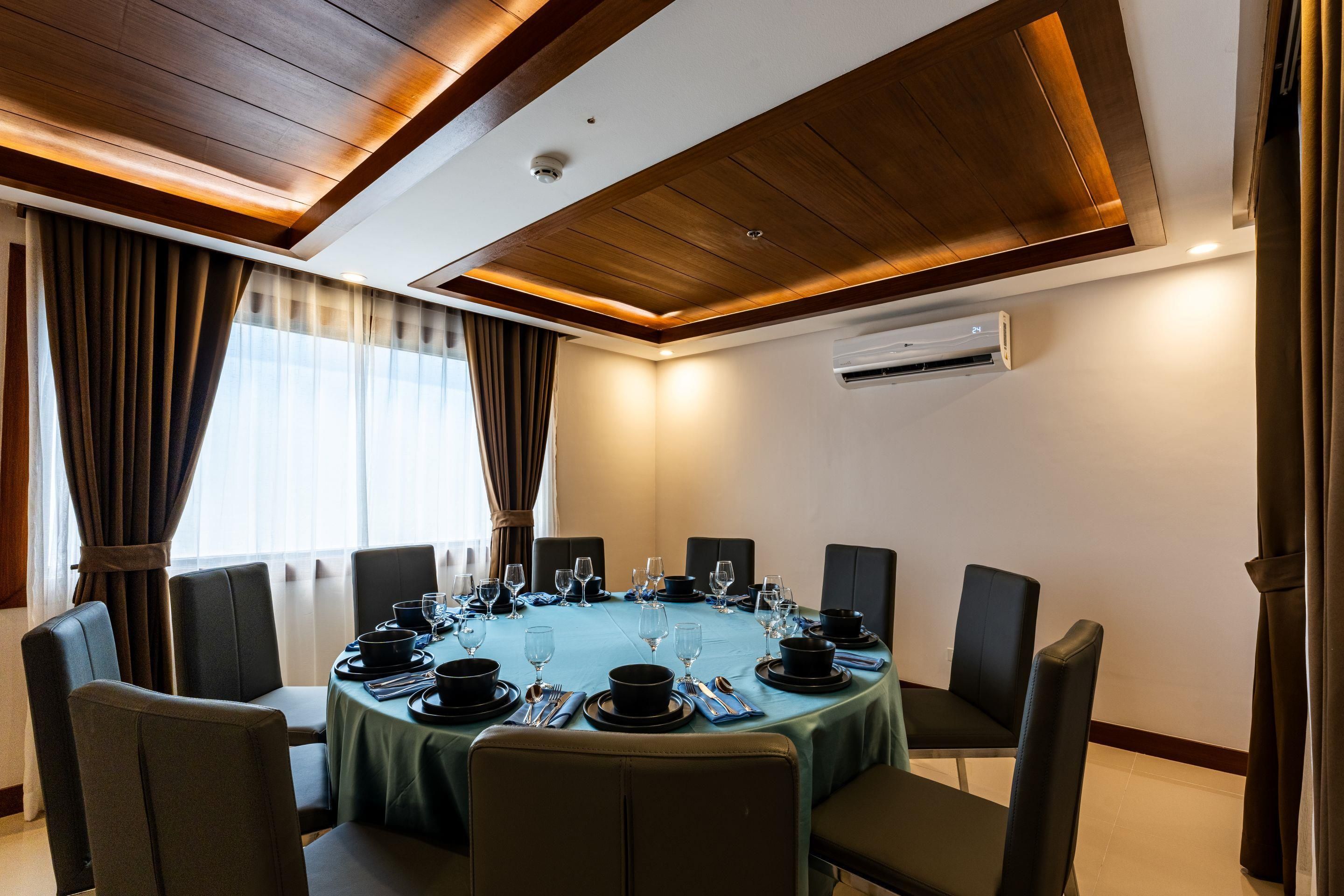 Un salón de conferencias con una mesa redonda, sillas y un equipo de aire acondicionado instalado en el techo.