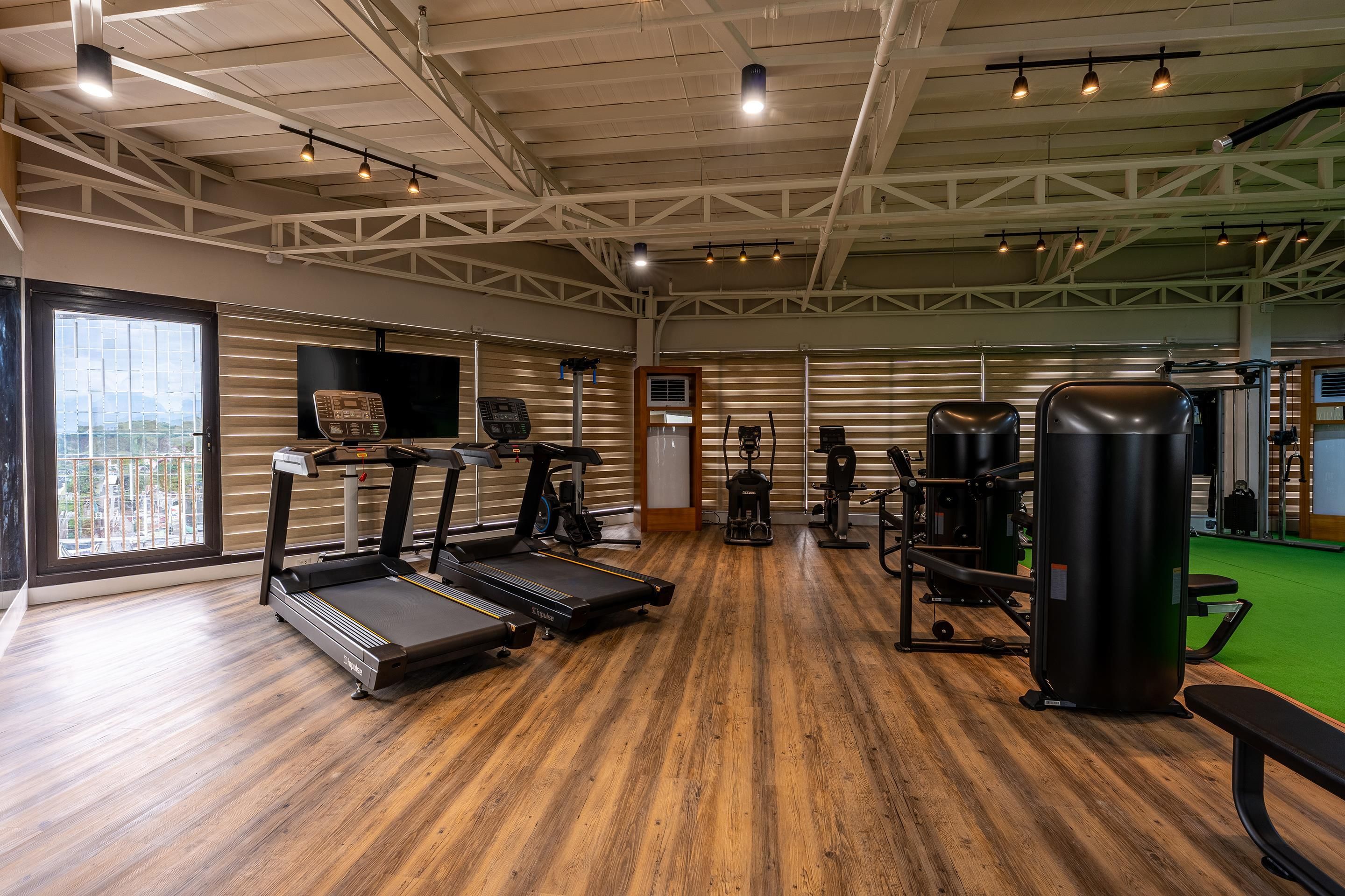 A gym with treadmills, weight machines, and a large mirror.