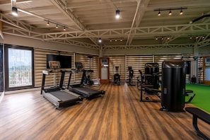 A gym with treadmills, weight machines, and a large mirror.