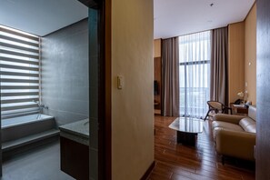 Une chambre d’hôtel moderne équipée d’une douche, d’un canapé, d’une table basse et d’une grande fenêtre avec des rideaux.