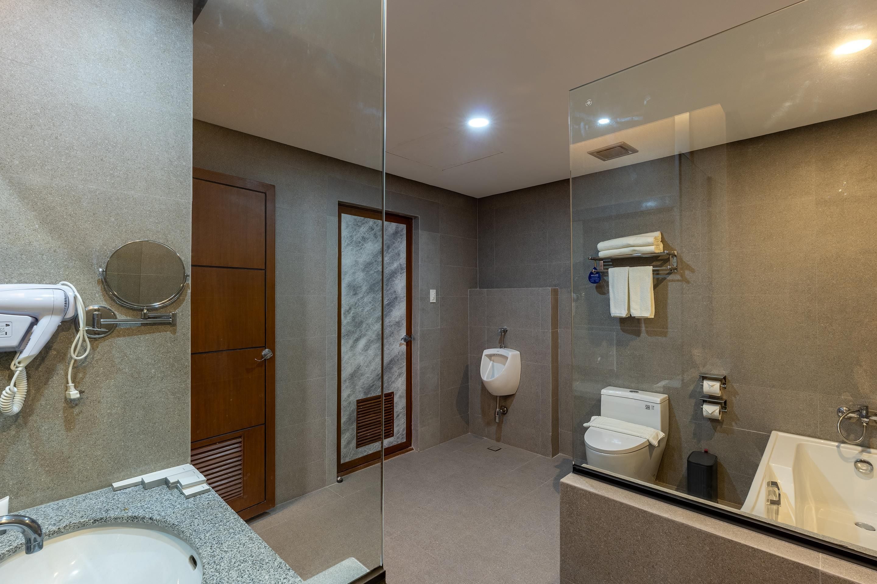 A modern bathroom with a granite countertop, a sink, a toilet, a bidet, and a glass shower enclosure.