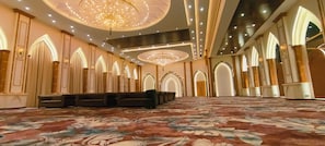 A spacious hall with a patterned carpet, arched doorways, and a chandelier.