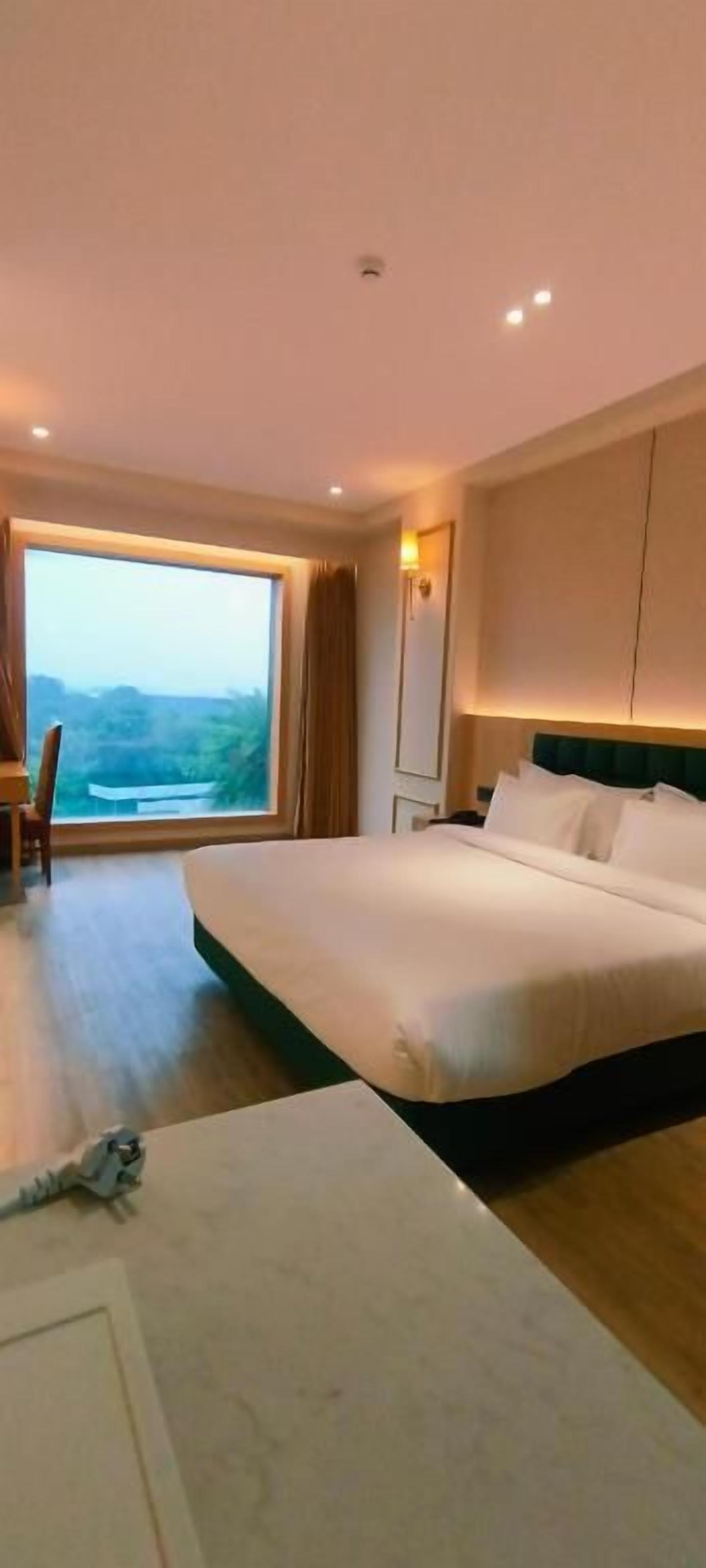 A hotel room with a large bed, a desk, and a view of the outdoors.