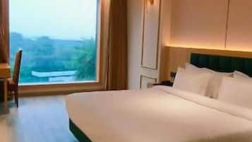 A hotel room with a large bed, a desk, and a view of the outdoors.