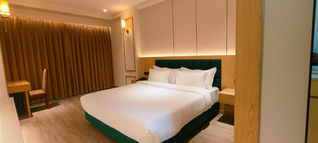 A hotel room with a large bed, a wooden nightstand, a desk, and a chair.