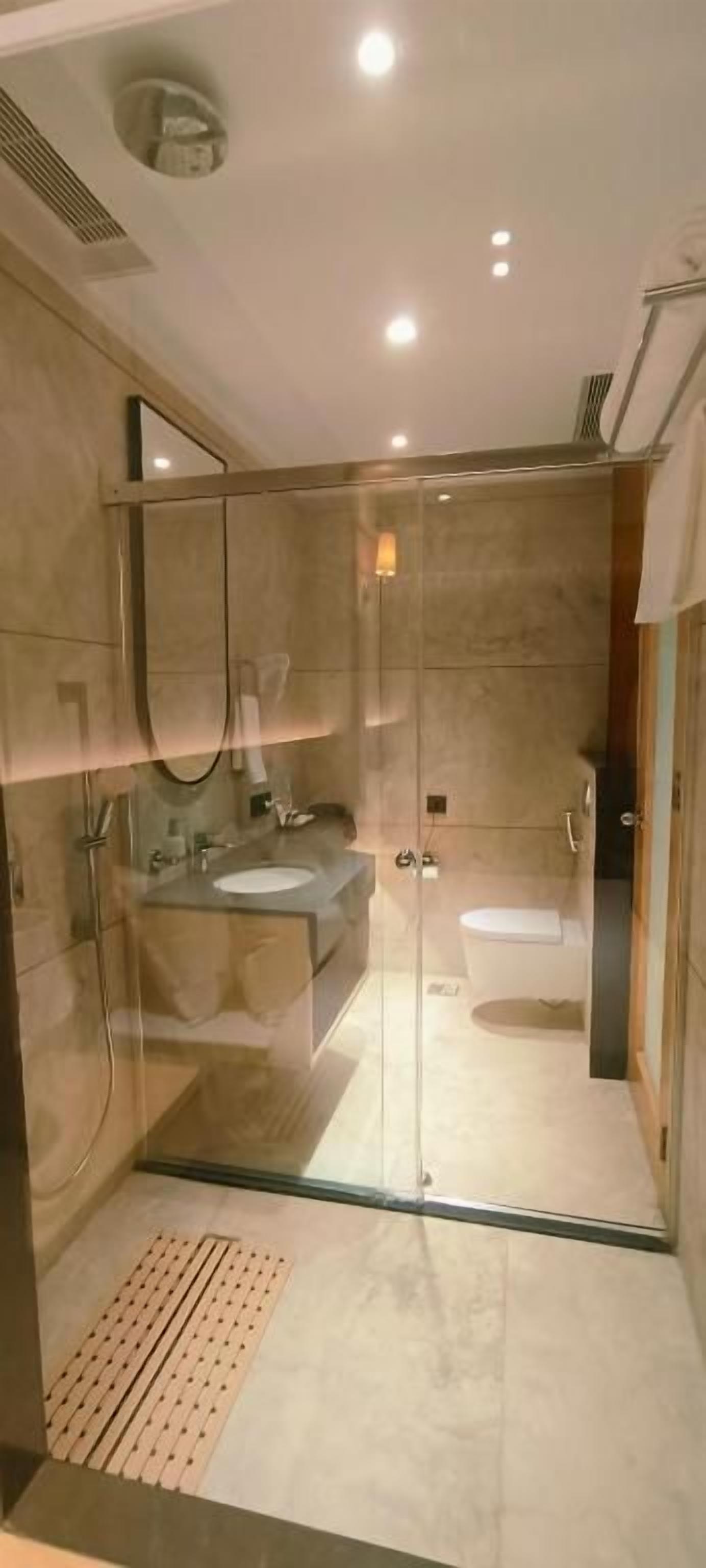 A modern bathroom with a glass-enclosed shower, a sink, and a toilet.