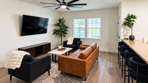 A modern living room with a sofa, armchairs, a coffee table, and a TV. - Howdy House | Private Party Deck • 2.5 Miles to A&M (College Station)