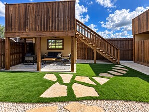 A wooden deck with a built-in seating area, a staircase, and a well-maintained lawn with stepping stones. - Howdy House | Private Party Deck • 2.5 Miles to A&M (College Station)