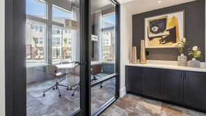 A modern office space with a glass door leading to a conference table and chairs, a dark cabinet with decorative vases, and a framed abstract painting on the wall. - Landing Amazing 1BD in Whitestone (Fort Worth)