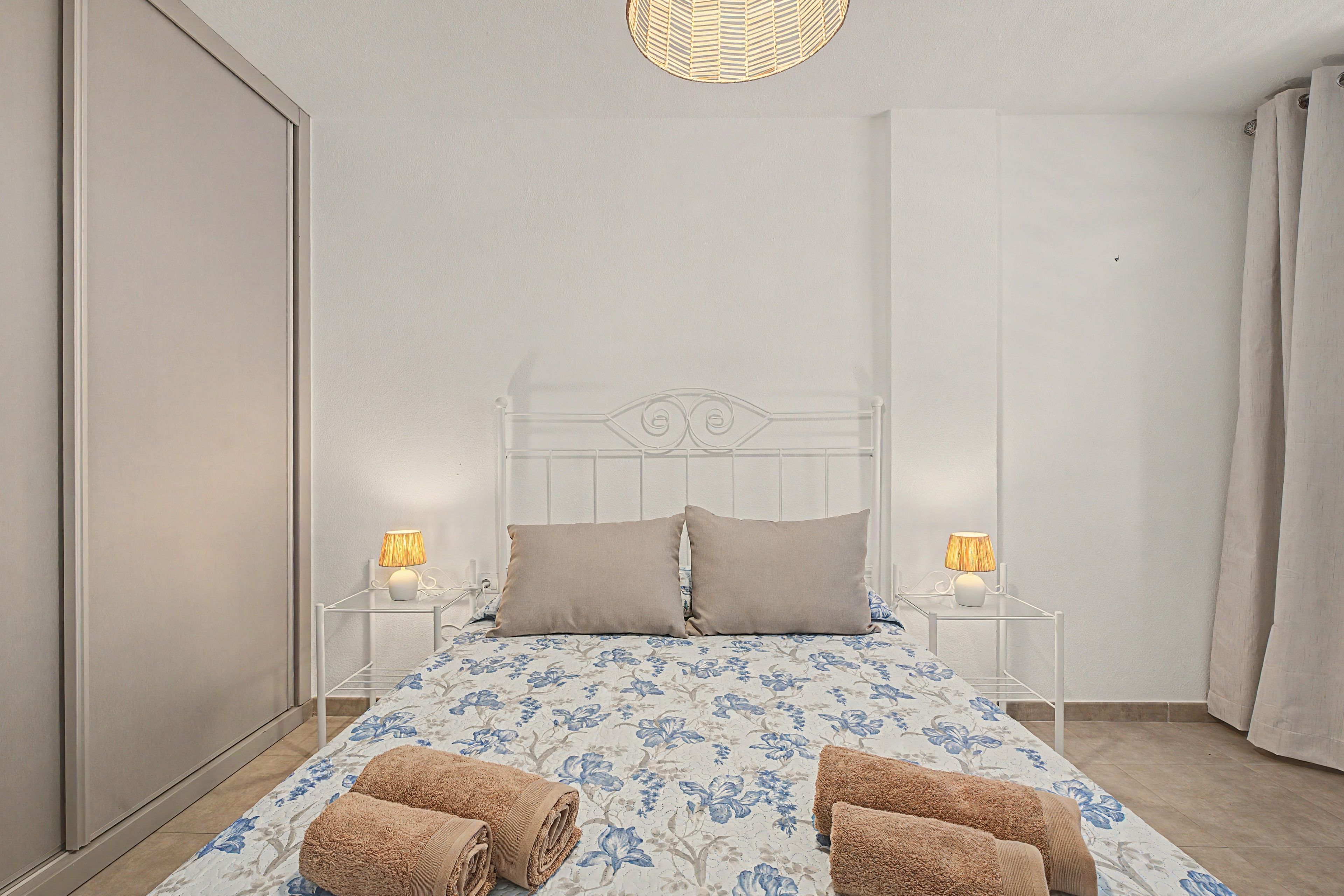 Une chambre à coucher avec un lit, deux lampes de chevet, une tête de lit et une fenêtre.