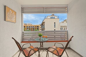 A balcony with a table and chairs, a window with blinds, and a framed artwork on the wall. - Holiday Apartment 'Los Playeros' with Balcony and Wi-Fi (Arona)