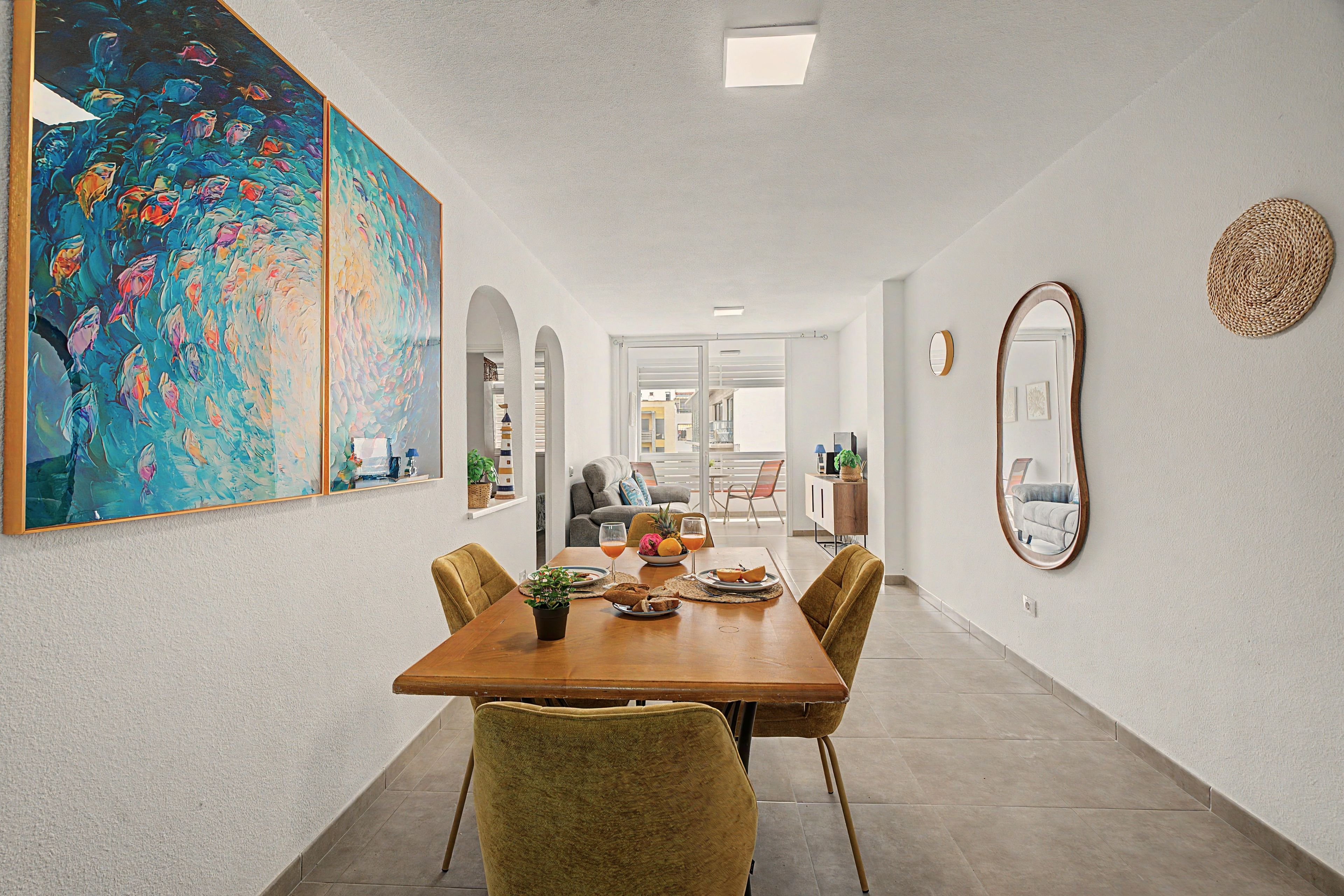 Un coin repas avec une table en bois, des chaises et un grand tableau accroché au mur.