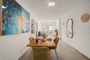 Een eetruimte met een houten tafel, stoelen en een groot schilderij aan de muur.