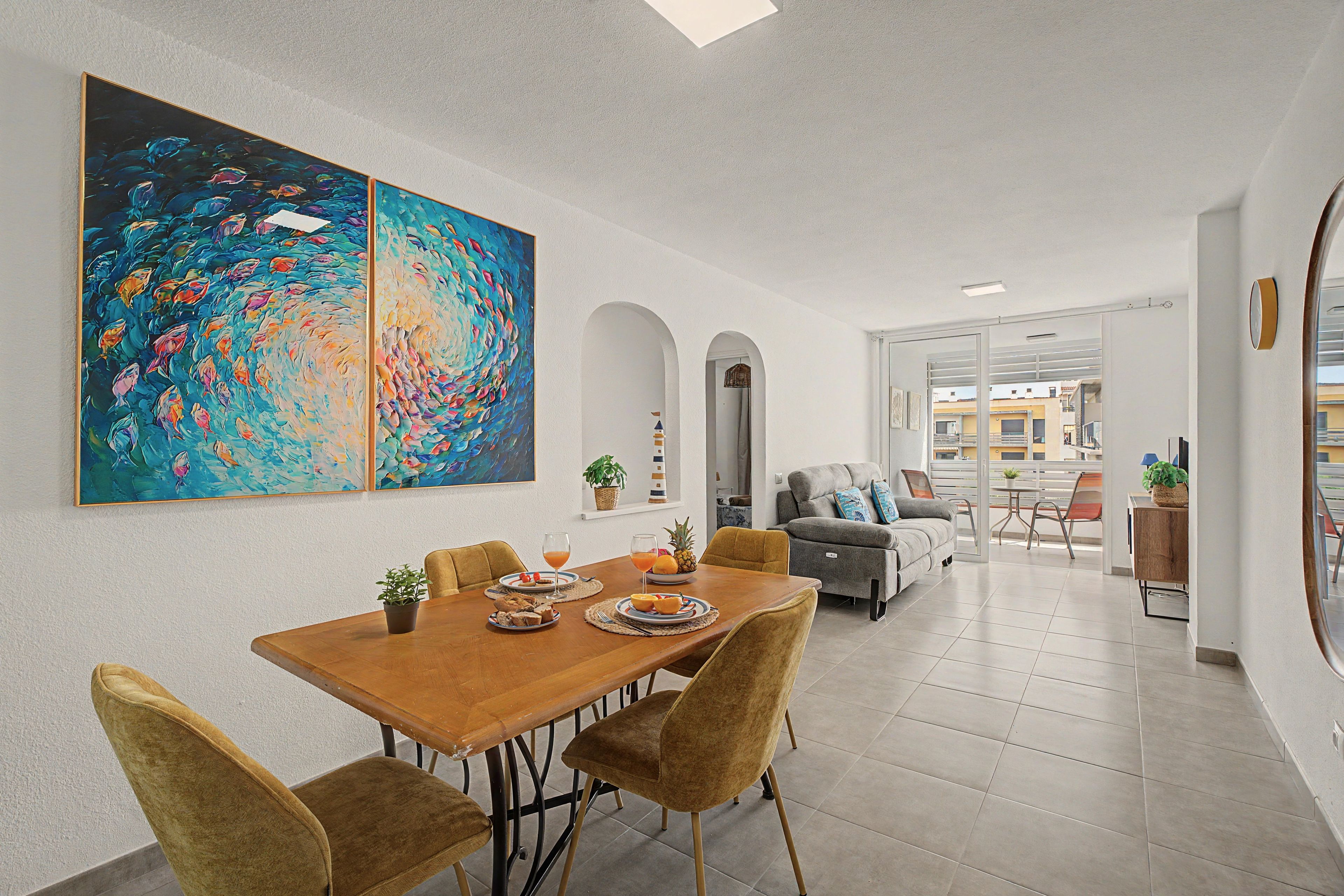 Un coin repas avec une table en bois, des chaises et un grand tableau abstrait accroché au mur.