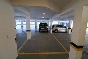A parking garage with multiple levels and columns, featuring cars parked in designated spaces. - Penthouse with sea view in Bombas (Bombinhas)