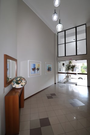 A spacious lobby with a wooden reception desk, a large mirror, and artwork on the walls. - Penthouse with sea view in Bombas (Bombinhas)