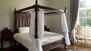 A four-poster bed with a canopy, a chandelier, a window with curtains, and a patterned rug. - Uppercourt Manor  (Freshford)