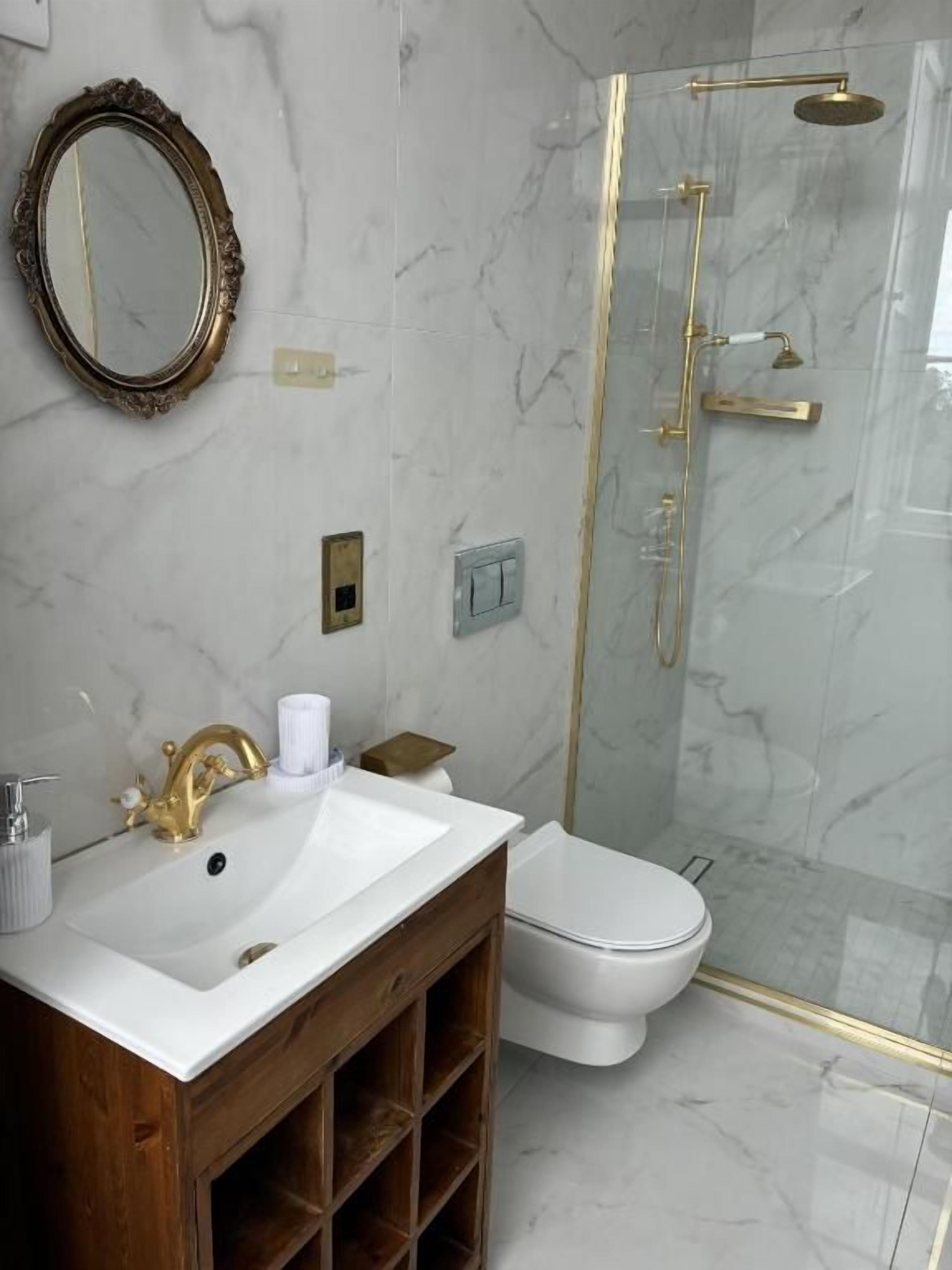 A bathroom with a marble sink, a toilet, and a glass-enclosed shower.