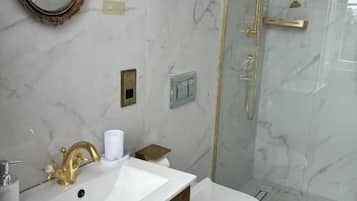 A bathroom with a marble sink, a toilet, and a glass-enclosed shower.