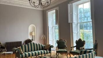 A room with striped sofas, a chandelier, and large windows.