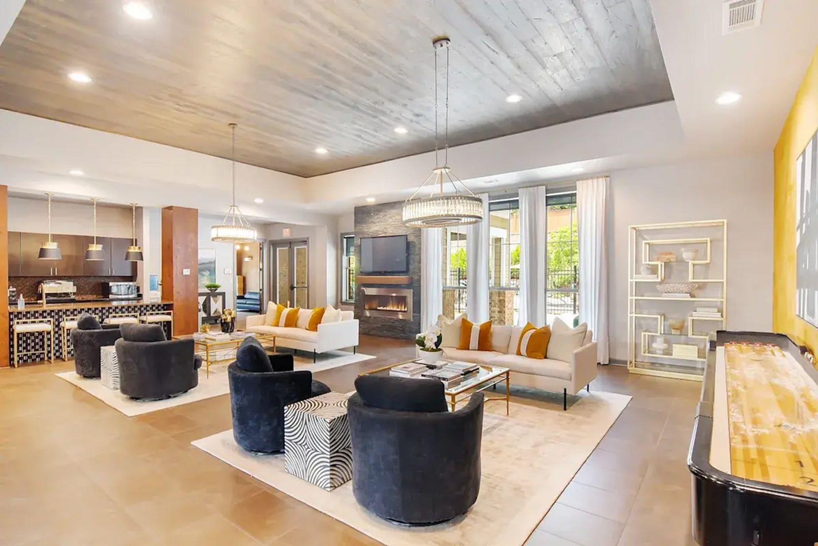 A spacious living area with a sofa, coffee table, and ottomans, a kitchen area, and a fireplace.