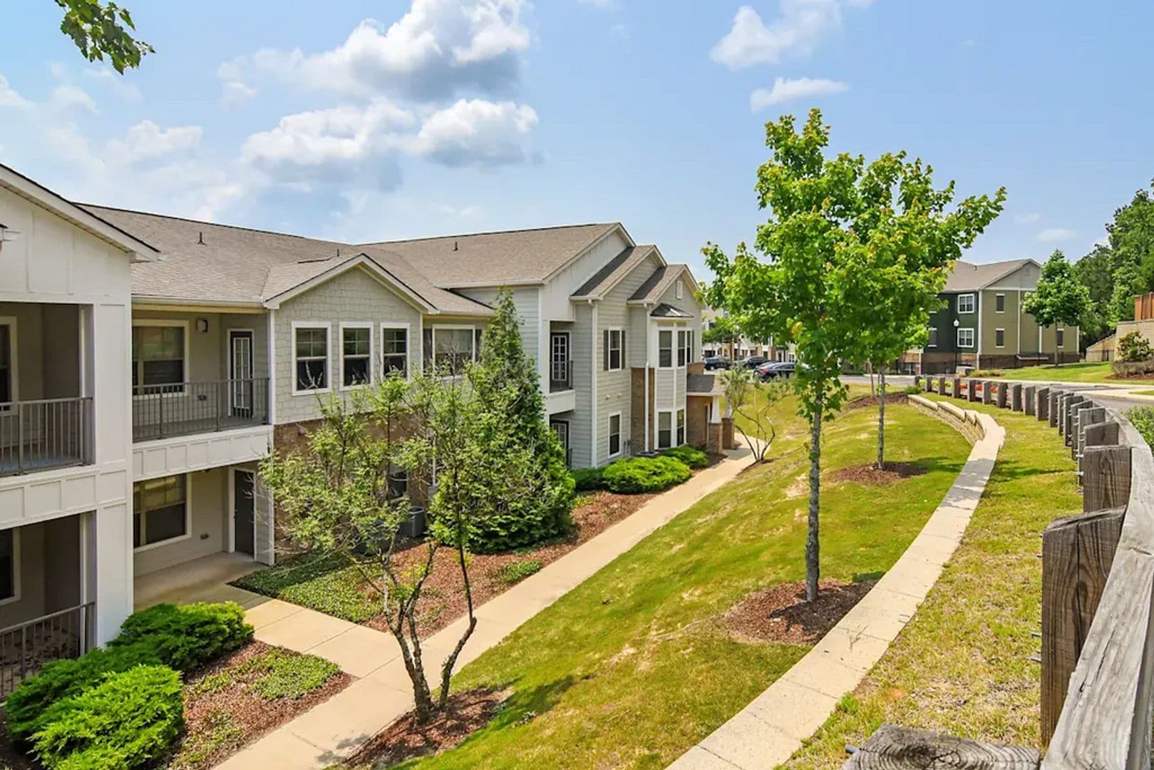 A residential complex with multiple two-story buildings, a central walkway, and small trees.