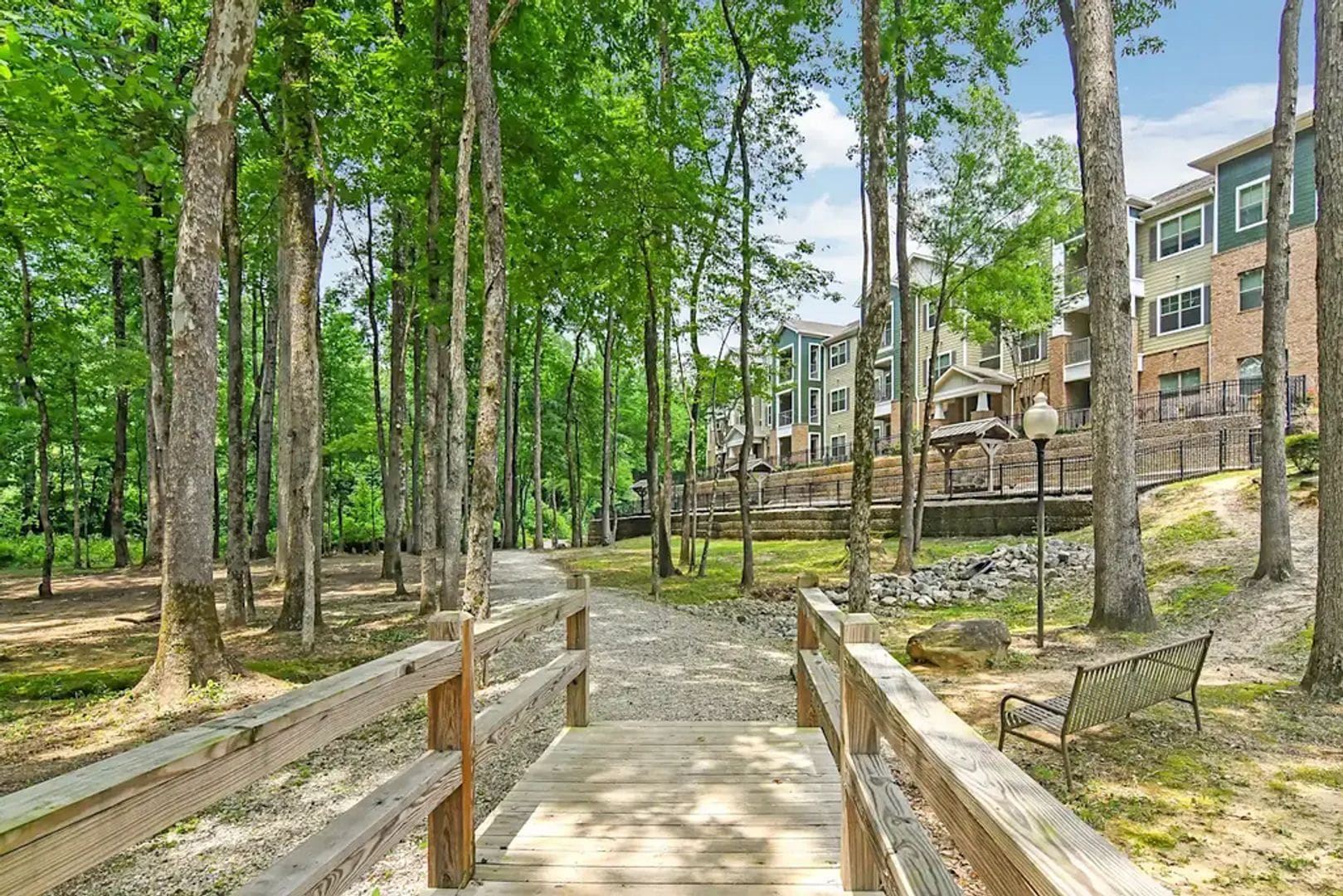 A wooden bridge leading to a building with multiple floors, surrounded by trees.