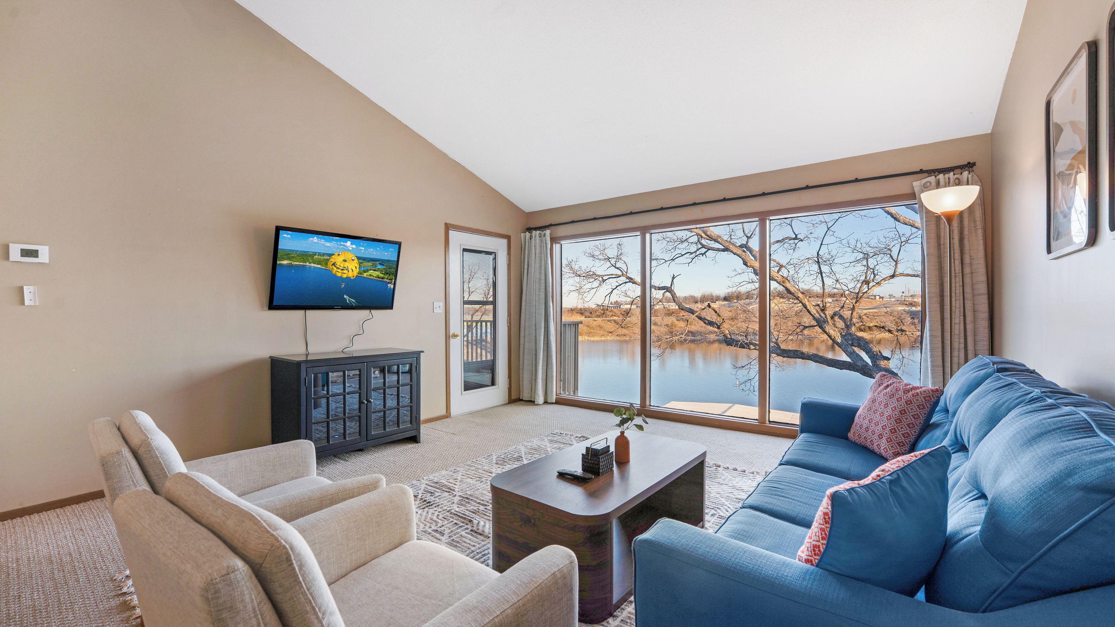 A living room with a large window, a flat-screen TV, a sofa, and a coffee table.