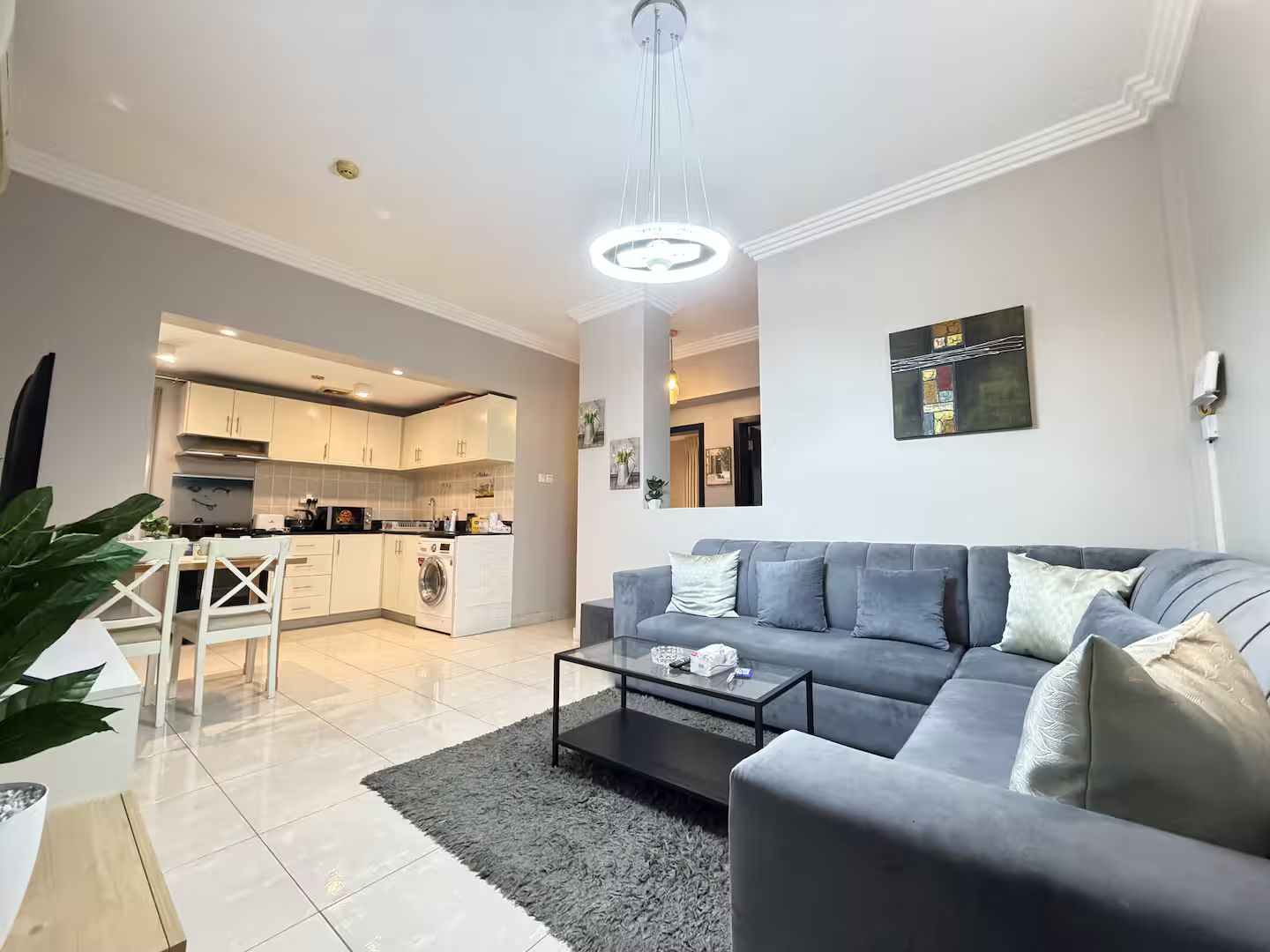 Een moderne woonkamer met een grijze bank, een salontafel en een keuken op de achtergrond.