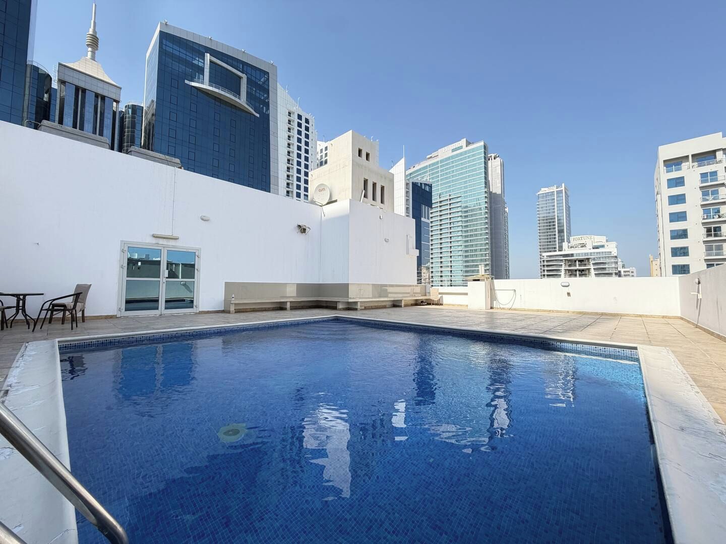Una piscina en la azotea con vistas despejadas a edificios altos circundantes.