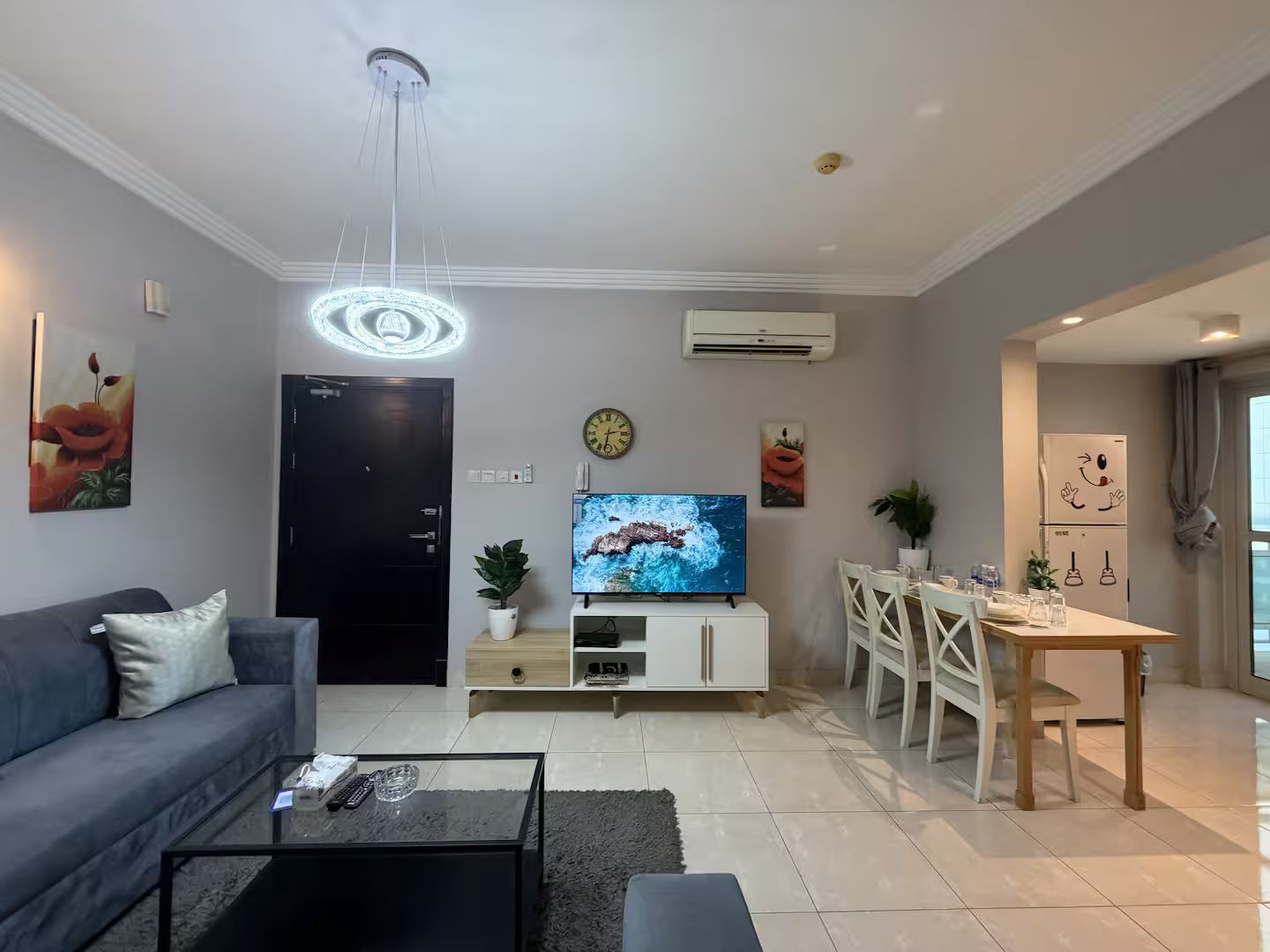 Una sala de estar moderna con sofá, mesa de centro, televisor y zona de comedor.