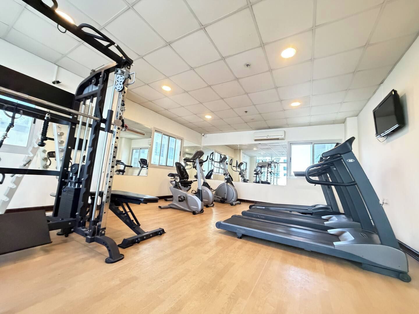 Un gimnasio con equipo de ejercicio, cintas de correr y un espejo.