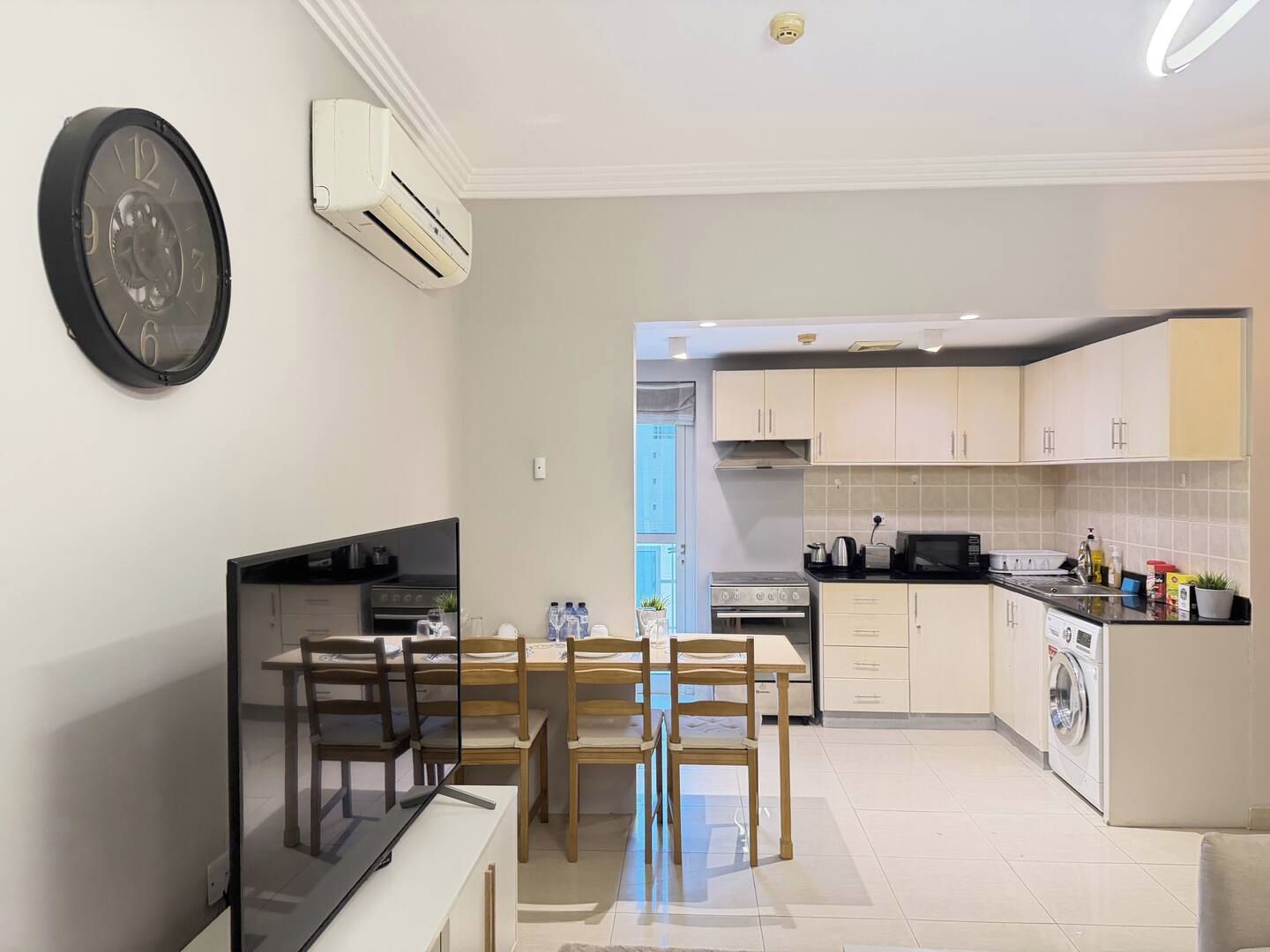 A modern kitchen with a dining area, a built-in oven, and a washing machine.