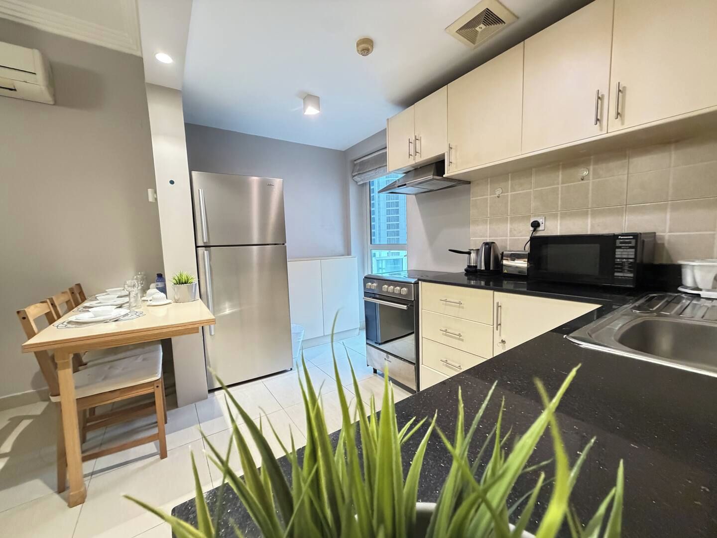 Una cocina moderna con electrodomésticos de acero inoxidable, un comedor con mesa de madera y vistas a la ciudad.