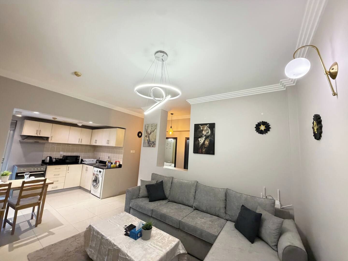 A modern living room with a grey sofa, a coffee table, and a dining area with wooden chairs.
