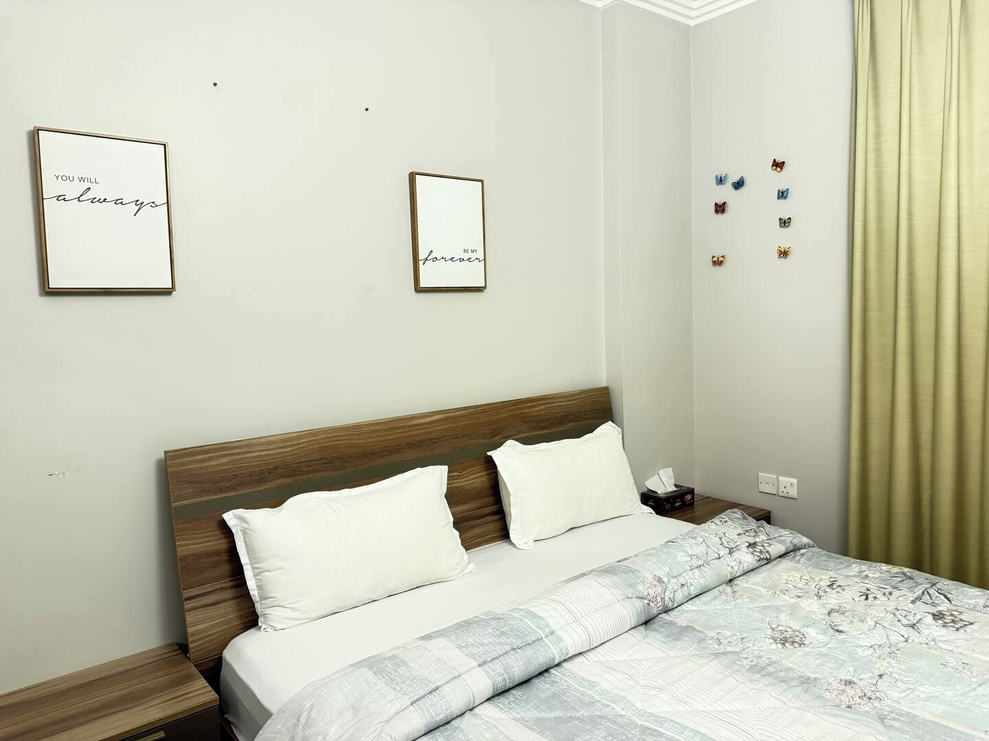 A neatly made bed with a patterned bedspread, two pillows, and a bedside table with a lamp.