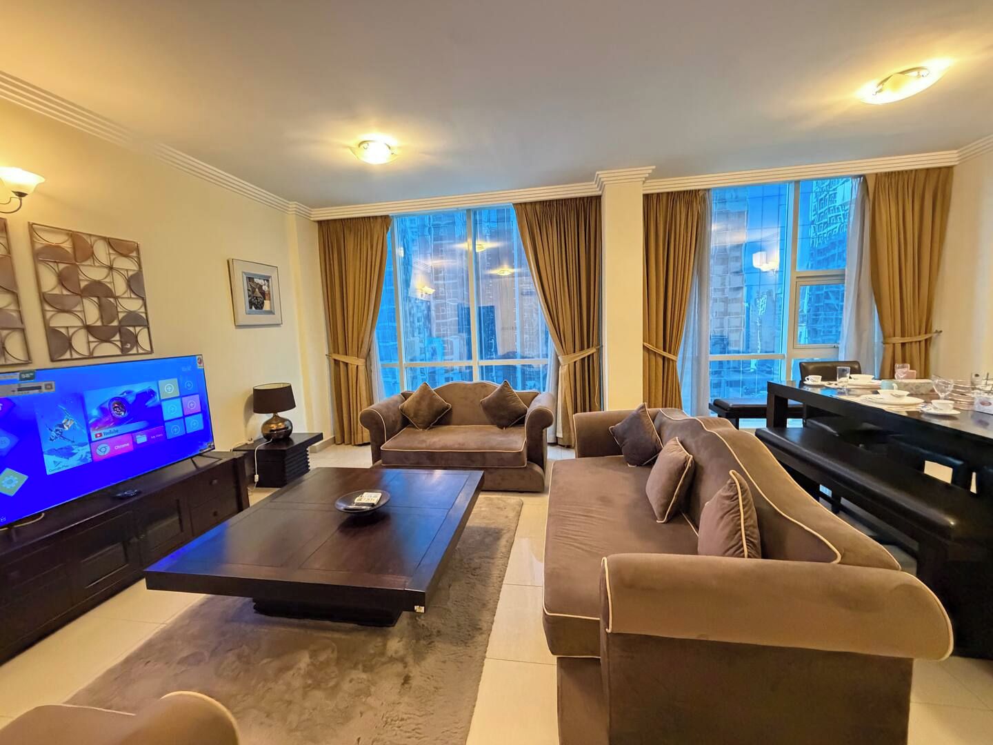 Ein Wohnzimmer mit Flachbildfernseher, einer Sofagarnitur, einem Couchtisch und einem Esstisch mit Stühlen.