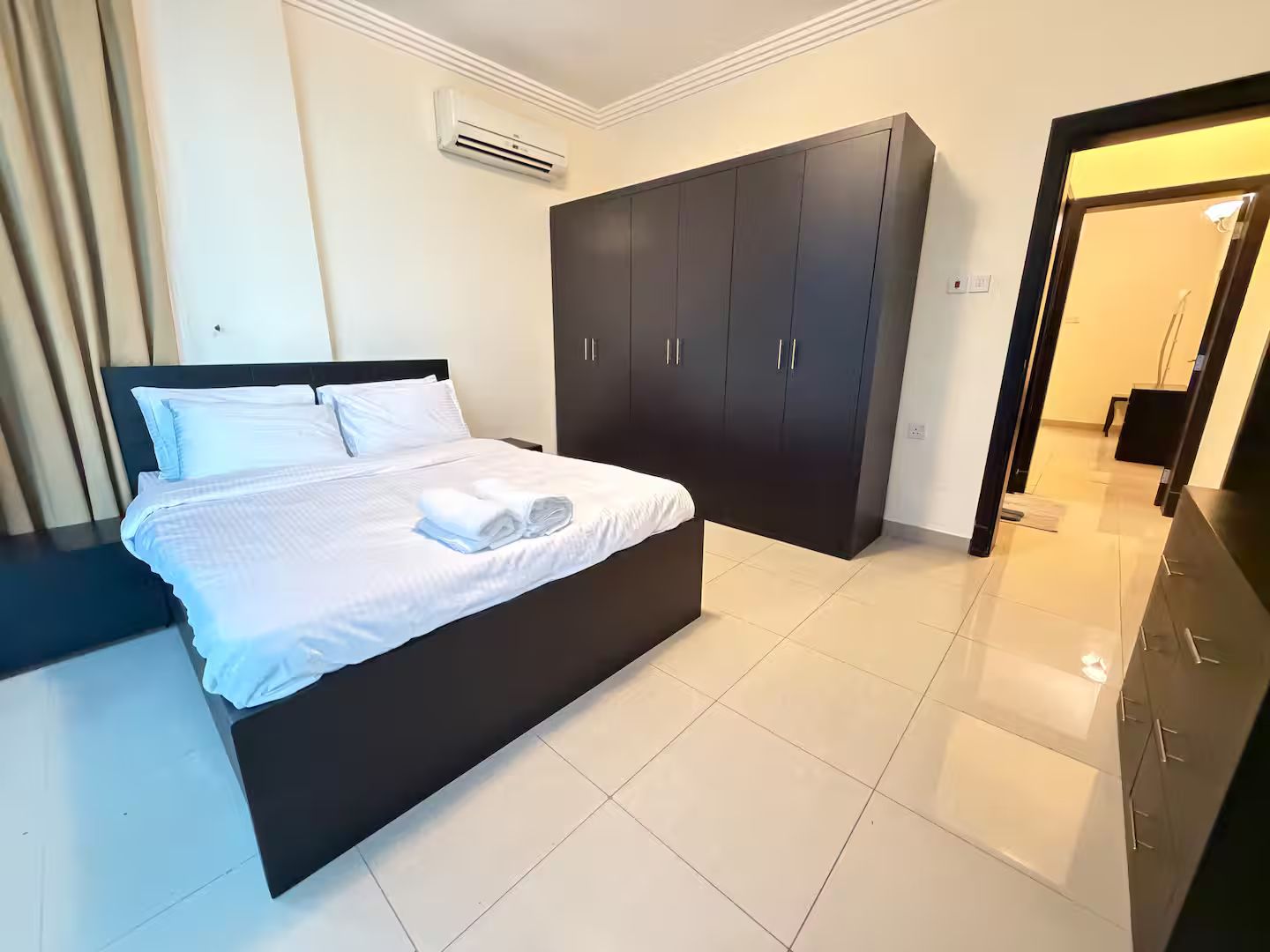 Una habitación de hotel con una cama, armario oscuro y equipo de aire acondicionado.