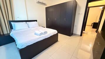 Una habitación de hotel con una cama, armario oscuro y equipo de aire acondicionado.