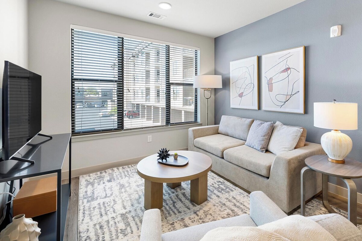 A modern living room with a sofa, coffee table, TV, and artwork on the wall.