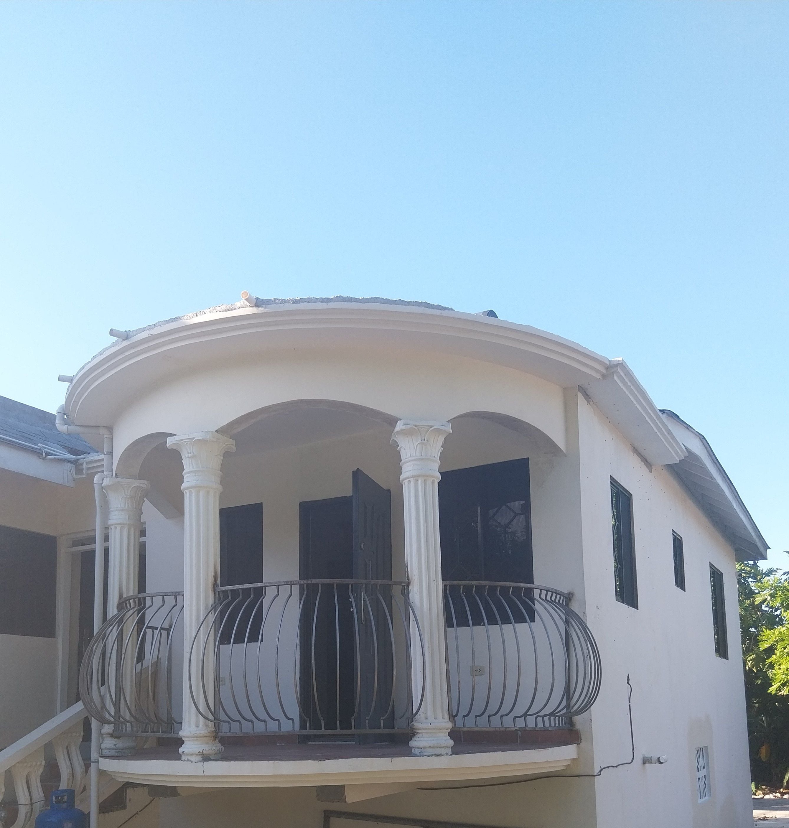 Un edificio con un balcone, colonne e una porta.