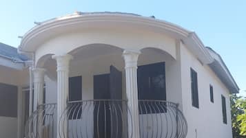 A building with a balcony, columns, and a door.