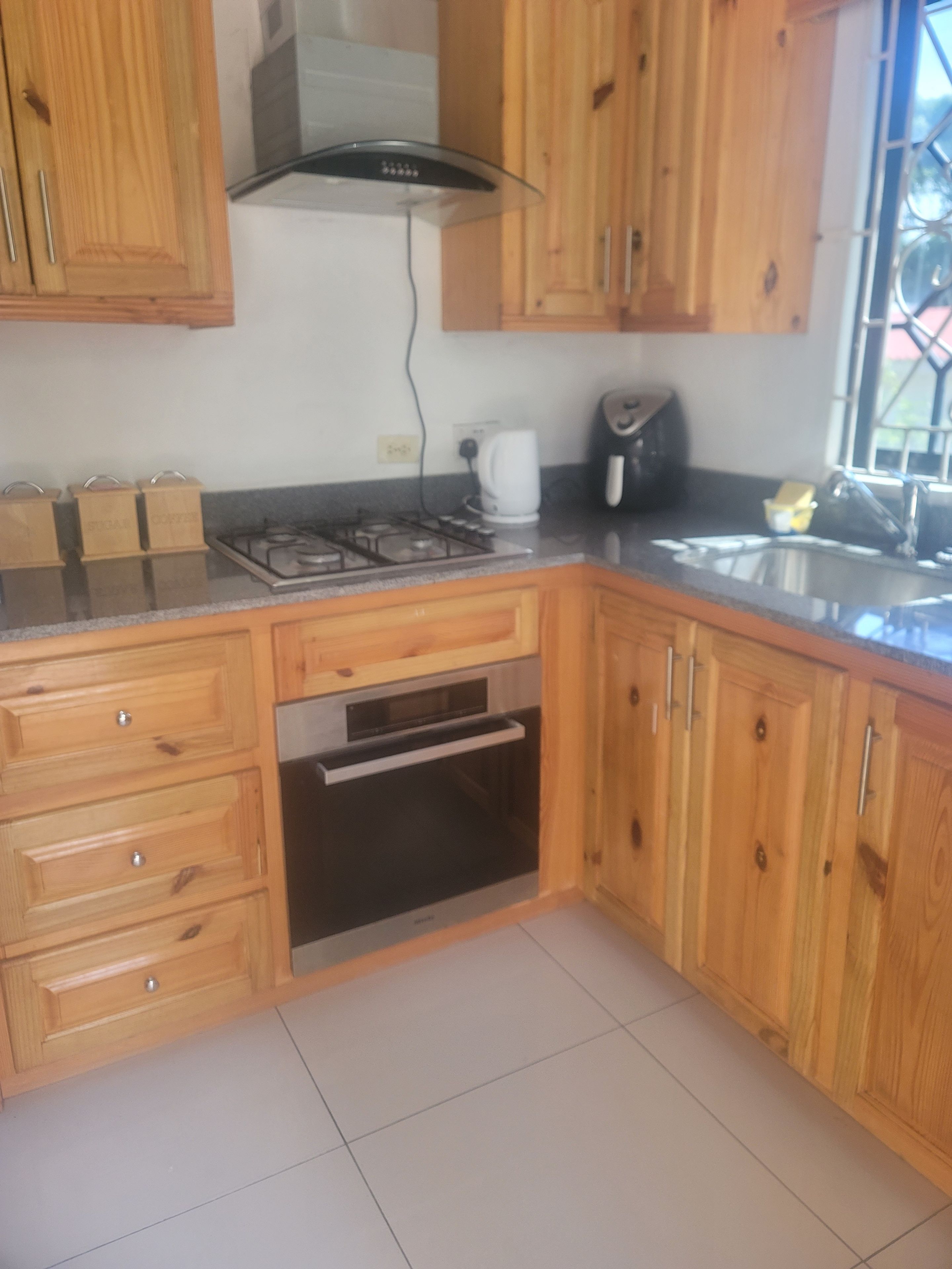 Una cucina con mobili in legno, un fornello a gas, un forno integrato e una finestra con vista.
