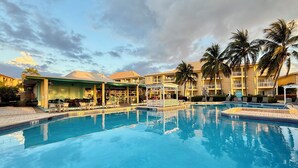 Un hotel con piscina, mobiliario exterior y palmeras.
