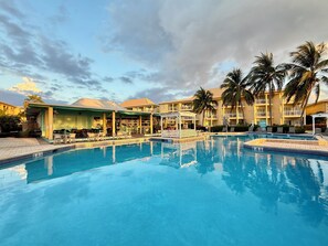 Un hôtel doté d’une piscine, d’un espace extérieur aménagé et de palmiers.